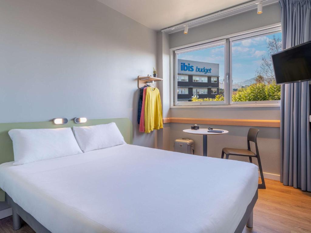 a hotel room with a bed and a window at Ibis Budget Barcelona Viladecans in Viladecáns