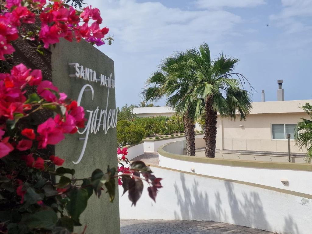 una señal frente a un edificio con flores rosas en Azalea Dreams by Santa Marija Estate en Mellieħa