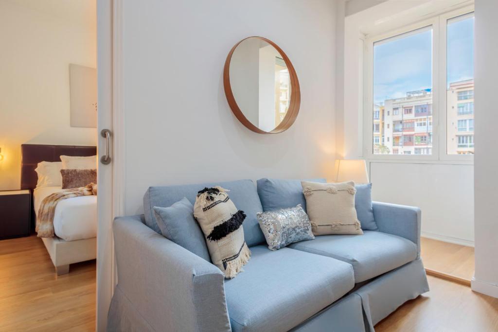 a blue couch in a living room with a mirror at Barcelonaforrent The Gaudí Suites in Barcelona