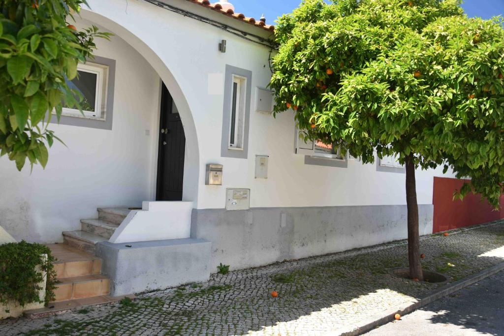 una casa blanca con un arco y un árbol en House of Love Portimão en Portimão