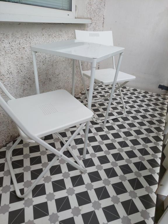 two white chairs and a table on a black and white floor at Komfort byt s parking zadarmo in Košice
