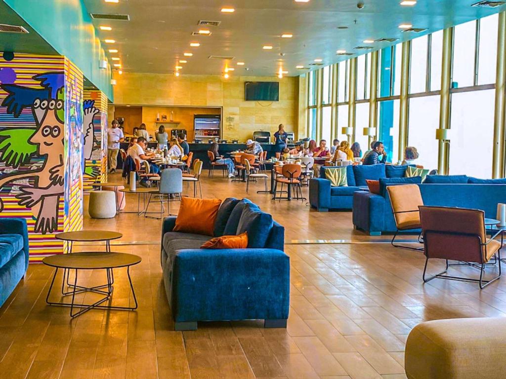 um lobby com sofás azuis e pessoas em um restaurante em Novotel Puerto Montt em Puerto Montt