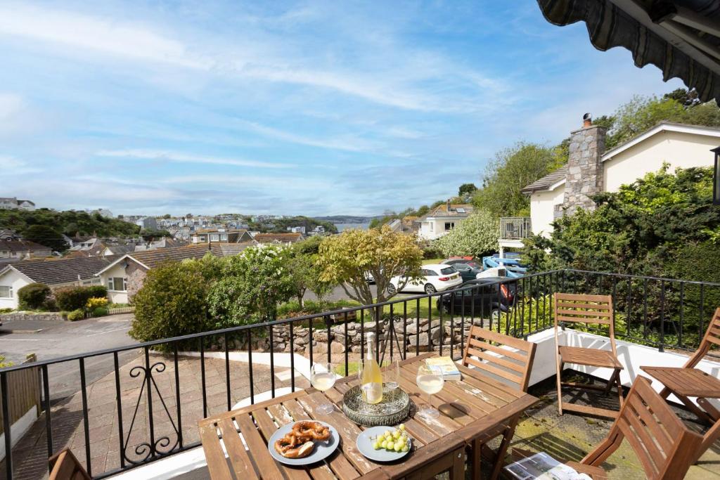 een balkon met een houten tafel en stoelen bij The Retreat, Brixham in Brixham