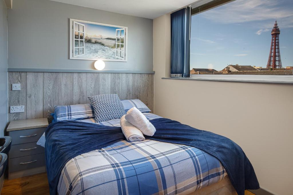 1 dormitorio con 1 cama y una ventana con un faro en Seaside Suites Superior Family Apartments, en Blackpool