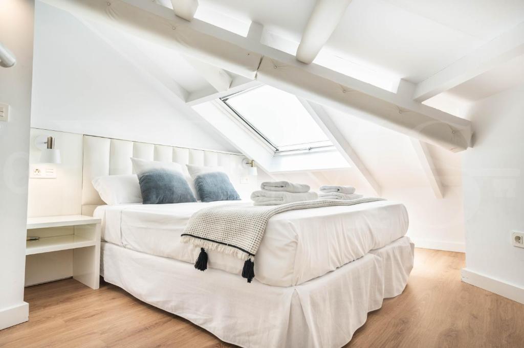 a white bedroom with a large white bed with blue pillows at Inviting duplex in front of Picasso Museum by REMS in Málaga