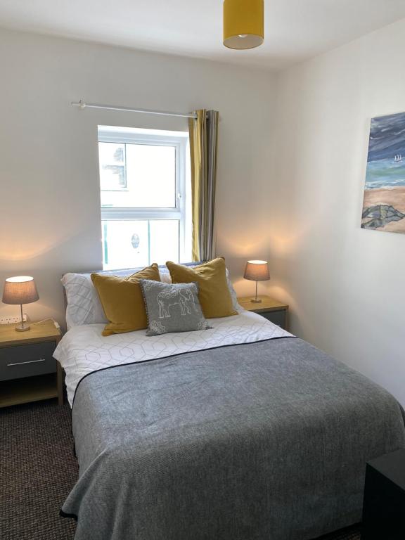 een slaapkamer met een bed met gele kussens en een raam bij The White House in Derry Londonderry