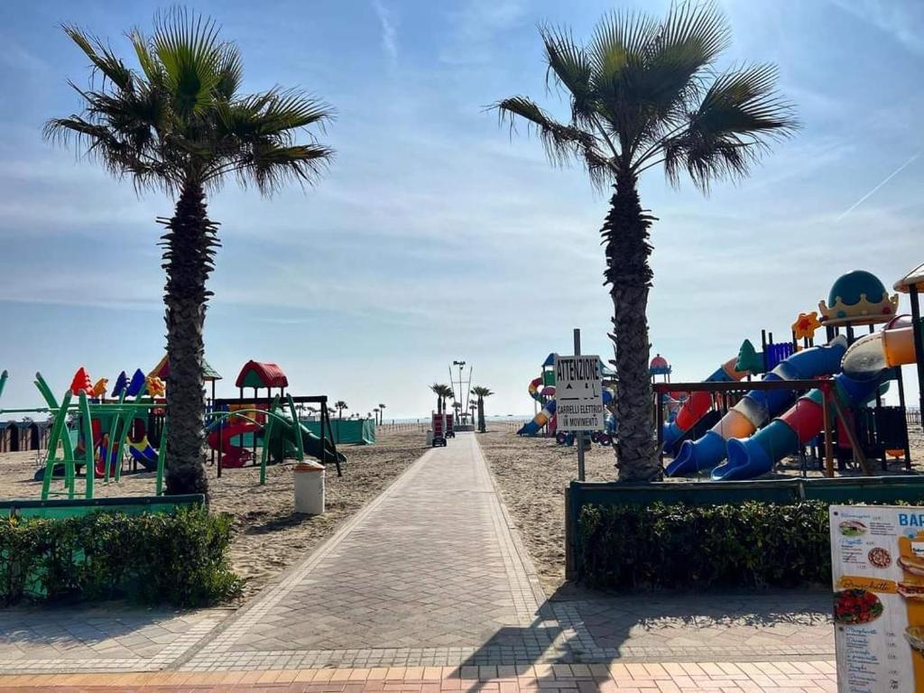 un parque infantil en la playa con palmeras y toboganes en Appartamento Perla Marina, en Sottomarina