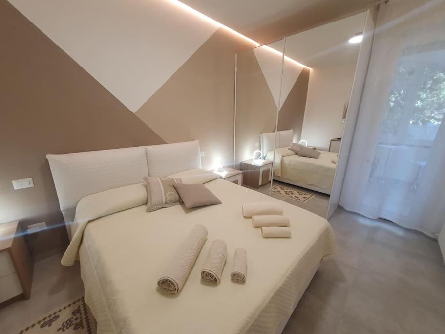 1 dormitorio con 1 cama blanca grande y zapatillas. en Lecci al Mare en San Vincenzo