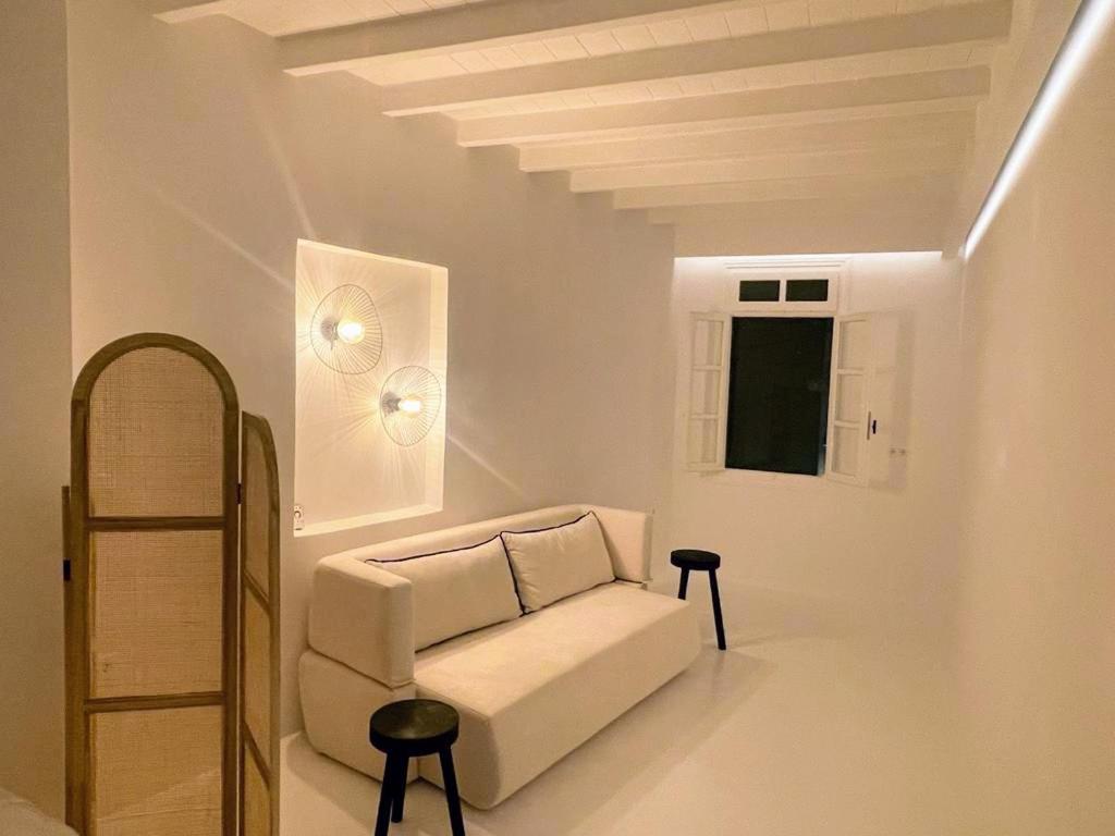 a white living room with a couch and a window at Studio 77 in Mikonos
