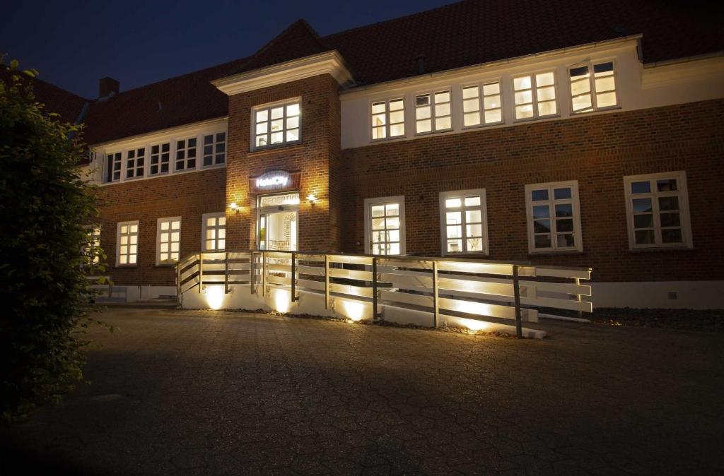 un bâtiment en briques avec une clôture devant lui la nuit dans l'établissement Hotelcity, à Holstebro