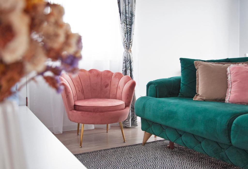 ein Wohnzimmer mit einem rosa Stuhl und einer grünen Couch in der Unterkunft Elis Apart in Oradea