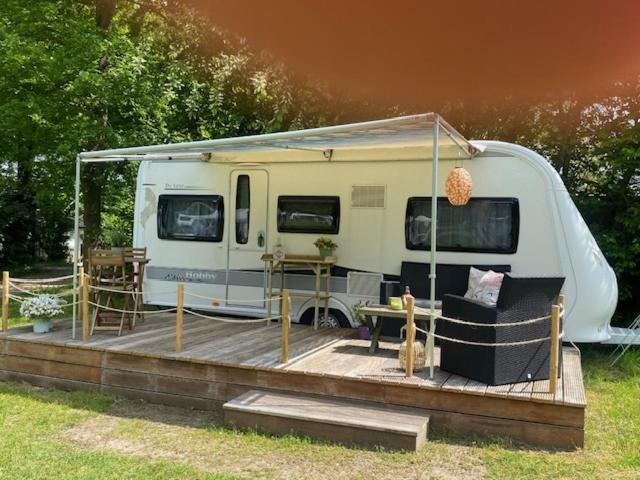 un rimorchio bianco con terrazza con tavolo e sedie di Caravan op Camping t Kopske in Den Hout a Den Hout