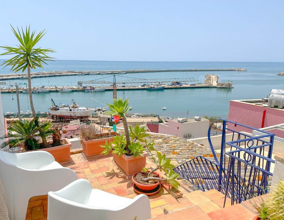 a balcony with white chairs and a view of the water at La casa del pescatore in Sciacca