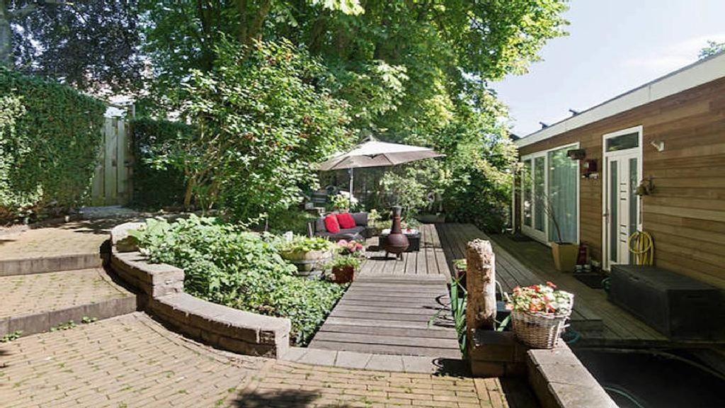 a backyard with a wooden deck with an umbrella at Studio in Woonboot + privébadkamer en -tuinterras in Utrecht