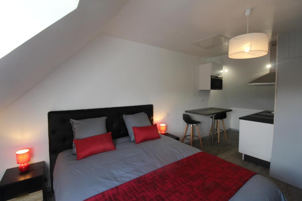 ein Schlafzimmer mit einem Bett mit zwei roten Kissen in der Unterkunft Chambre salle de bain wc et cuisine privé proche centre ville in Loudéac