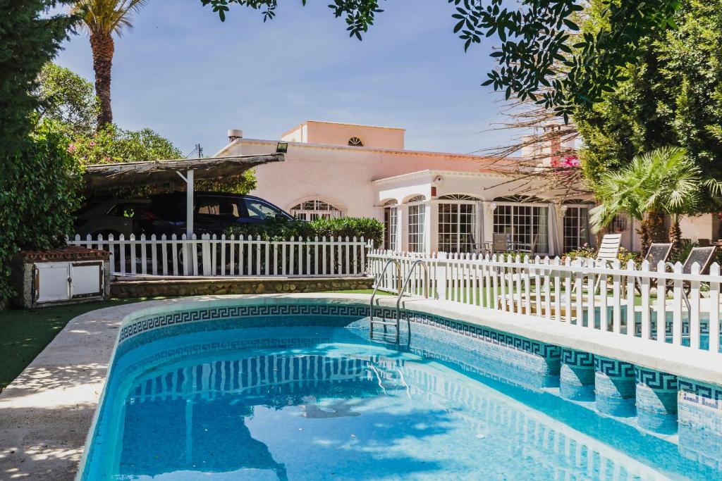 une piscine en face d'une maison avec une clôture blanche dans l'établissement Cortijo EL LLANO, à Almería