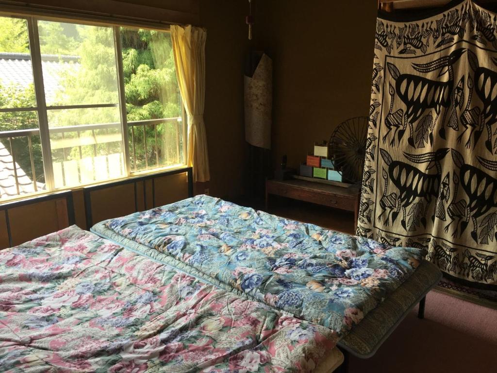 1 cama en un dormitorio con ventana en Guesthouse In Lak'ech - Vacation STAY 03558v, en Kami-ikusaka