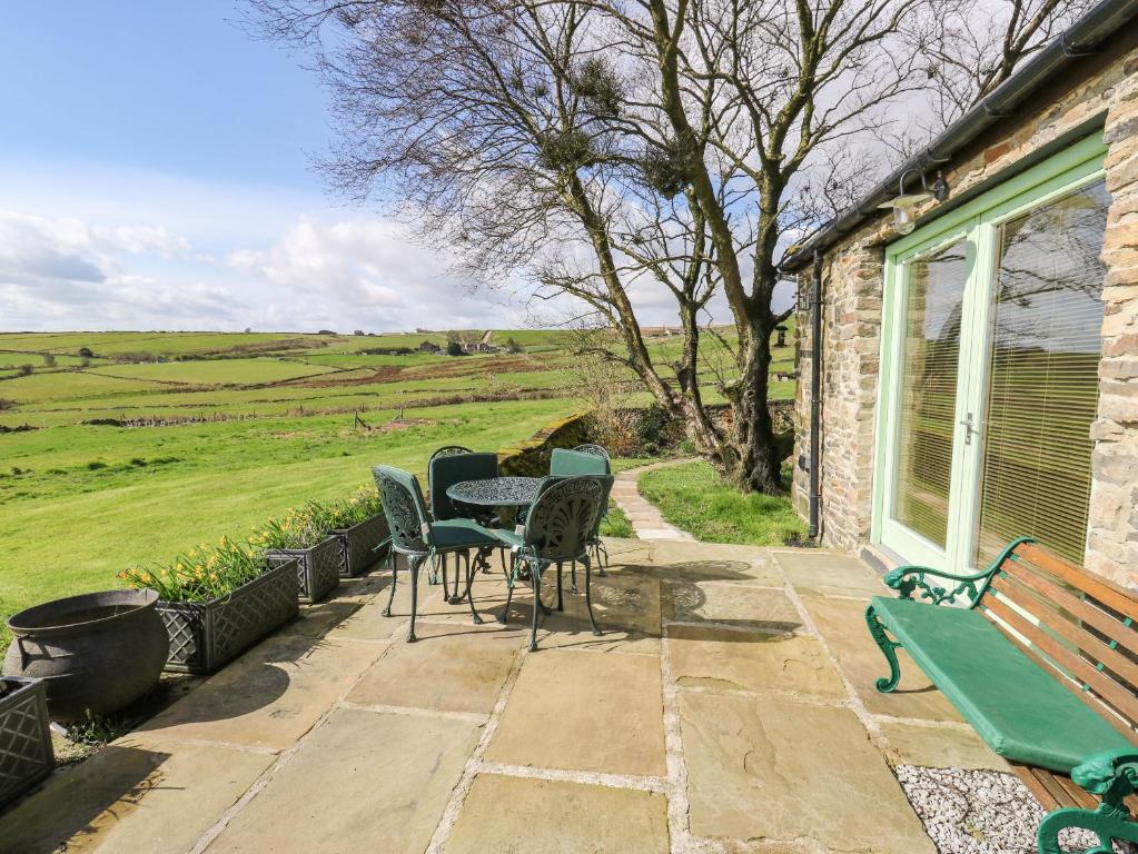 a patio with chairs and a table and a bench at The Barn at Crow Hill Shaw Farm in Sowerby Bridge