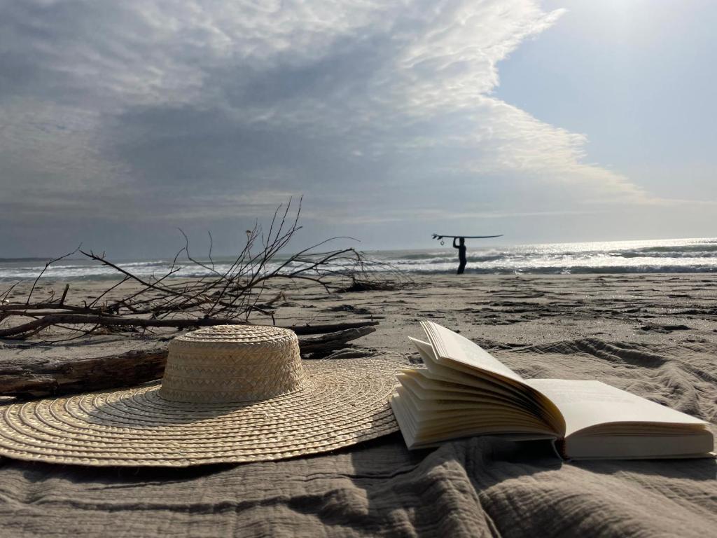 un sombrero de paja y un libro abierto en una playa en Sea House, en Viana do Castelo