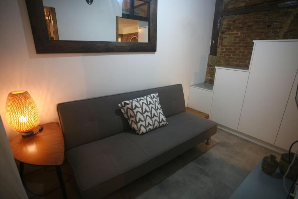 sala de estar con sofá, lámpara y espejo en Coqueto Estudio en Malasaña, en Madrid