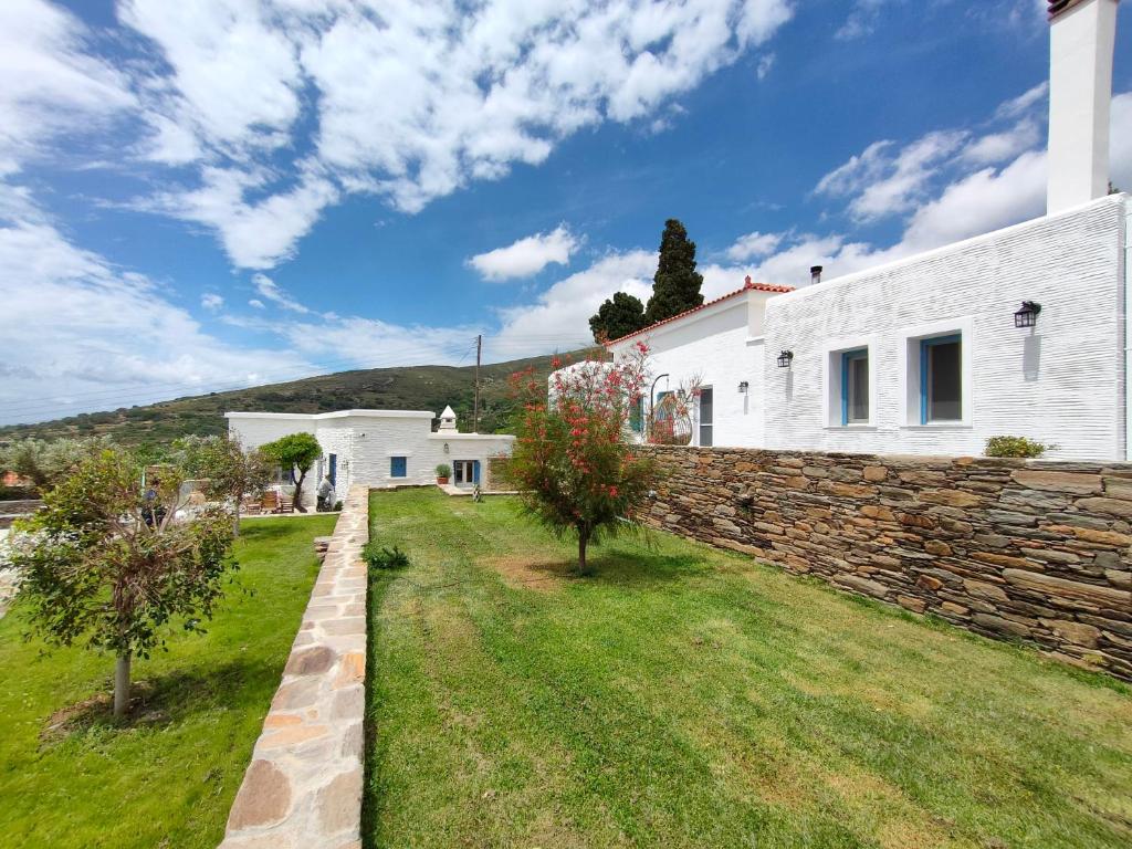 a house with a stone wall and a yard at Amarienitas Suites in Andros