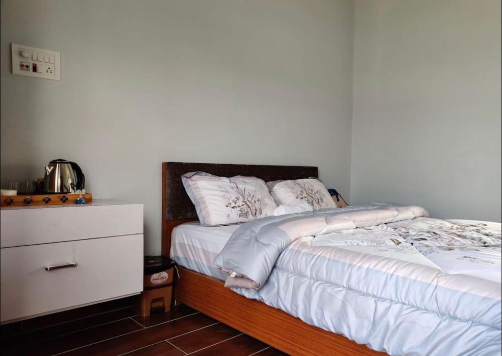 sypialnia z łóżkiem z białą pościelą i komodą w obiekcie Gracia Locus- Home Comfort w Dimapur