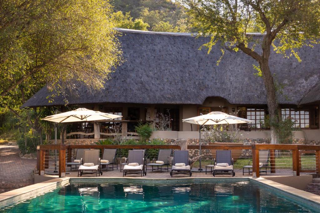 una piscina con sillas y sombrillas junto a un edificio en MILIMA Big 5 Safari Lodge, en Hoedspruit