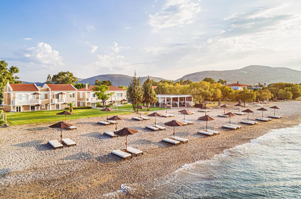 una fila de sombrillas y sillas en una playa en Doryssa Coast Apartments, en Pythagoreio