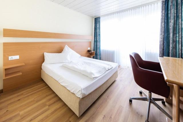 a bedroom with a bed and a desk and a chair at Hotel ISG Heidelberg in Heidelberg