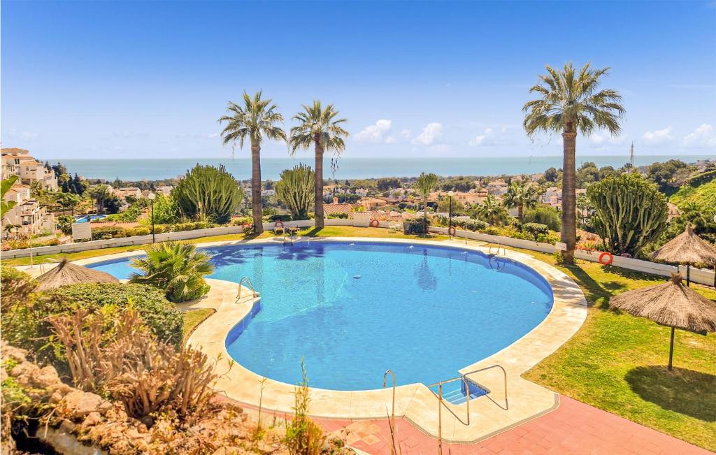 ミハス・コスタにあるAmazing Apartment In Mijas Costa With Swimming Poolのヤシの木と海を望む大型スイミングプール