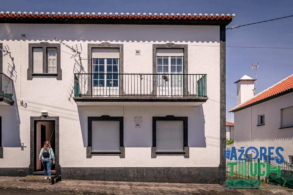 a woman standing in the doorway of a white house at Casa do Mirante in Praia da Vitória