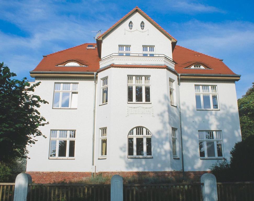 ein großes weißes Gebäude mit rotem Dach in der Unterkunft Villa Daheim - FeWo 03 in Ostseebad Kölpinsee