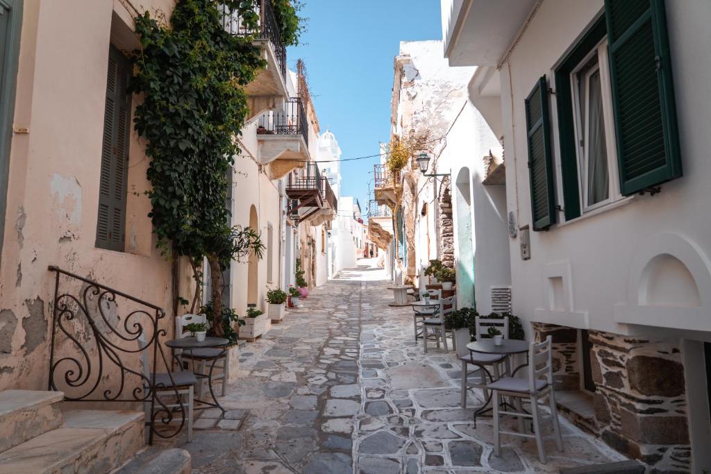 an alley in an old town with tables and chairs at Aggelikoula Rooms in Tinos