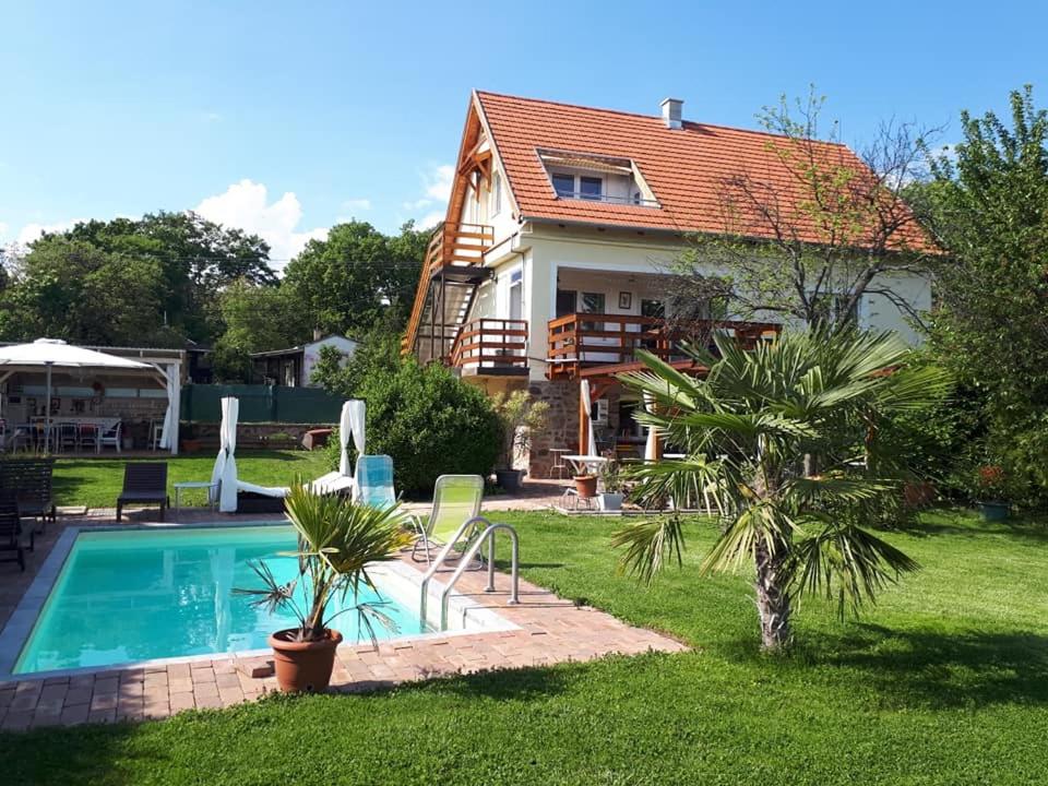 a house with a swimming pool in the yard at Fülöp Villa Apartmanház in Balatonszepezd