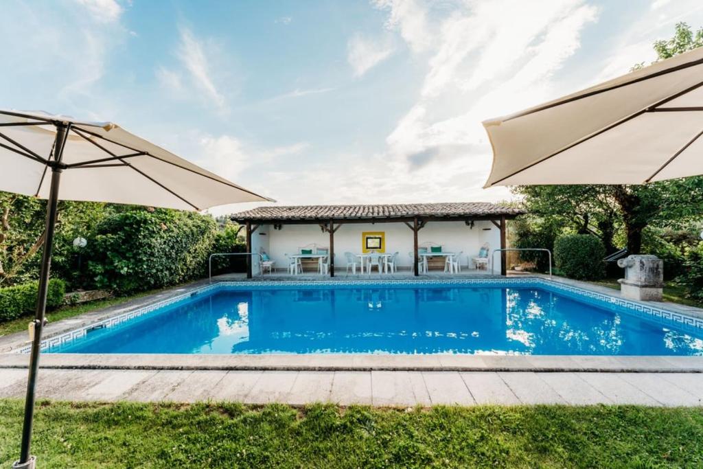 a swimming pool with an umbrella and a house at Quinta de S. Miguel 'Casa Das Oliveiras in Fundão