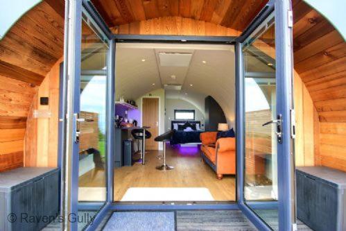 - un salon avec une paroi en verre dans une maison dans l'établissement Raven's Gully - Brodick, Isle Of Arran, à Brodick