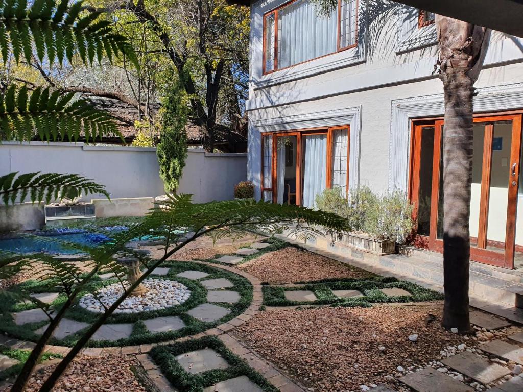 a garden in front of a white house with a tree at Troas Boutique hotel in Vanderbijlpark