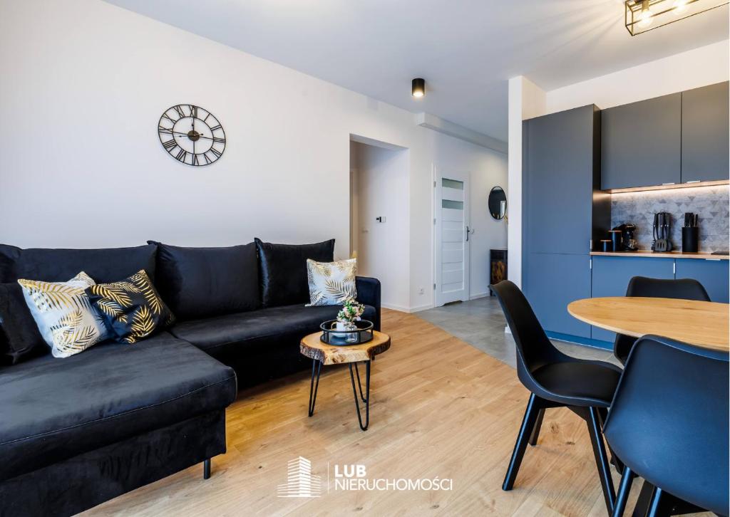 uma sala de estar com um sofá preto e uma mesa em Apartament Premium em Rzeszów