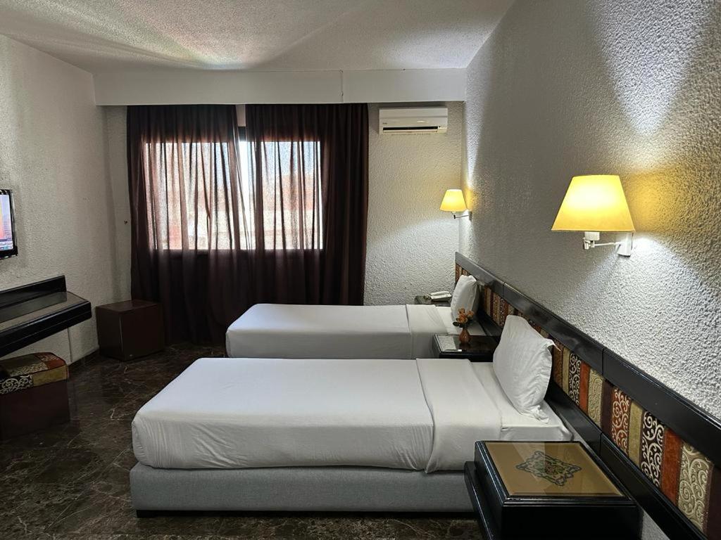 una camera d'albergo con due letti e una televisione di Ourida Urban Hotel Rabat a Rabat