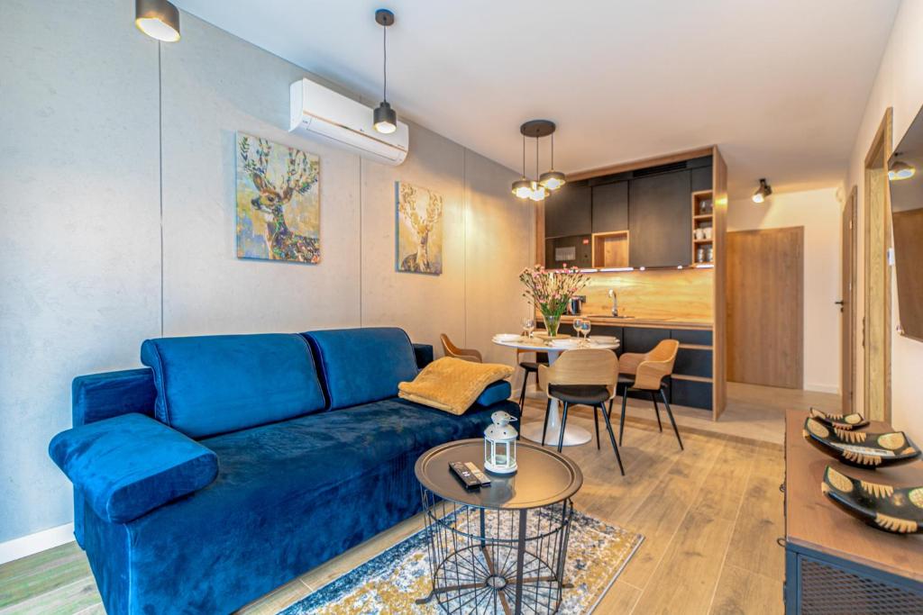 a living room with a blue couch and a table at Apartamenty Kalinowa z sauną i bawialnią - Dream Apart in Szczyrk