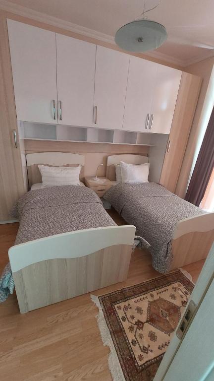 Habitación pequeña con 2 camas y alfombra. en Aurora appartment en Tirana