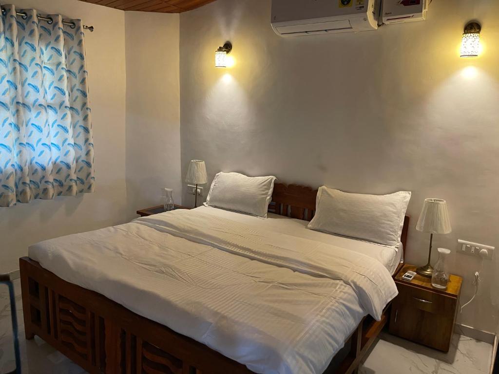 a bedroom with a large bed with white sheets and pillows at Sunset point 99 in Revadanda