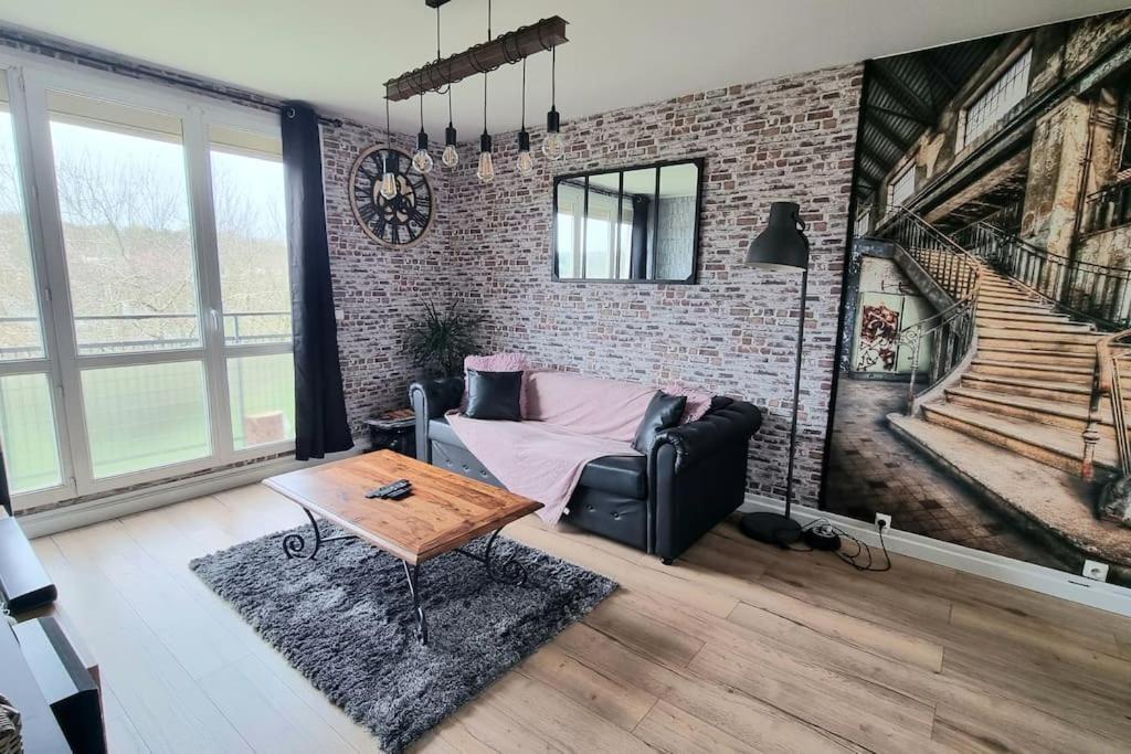 uma sala de estar com um sofá e uma parede de tijolos em Chez karole proche gare direct Paris em Coulommiers
