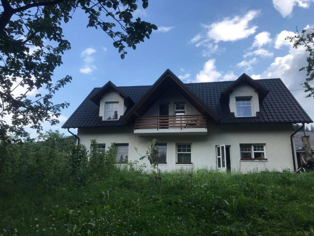 a house with a black roof on a hill at Pensiunea Agroturistica Cristal in Suceviţa