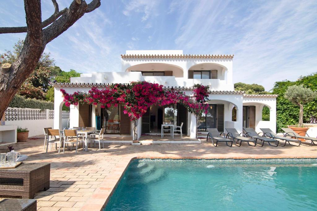 uma villa com piscina em frente a uma casa em Casa Quarenta Garrão na Quinta do Lago