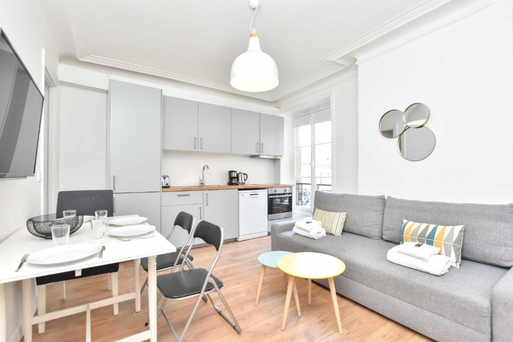ein Wohnzimmer und eine Küche mit einem Sofa und einem Tisch in der Unterkunft Lovely flat 4 P Palais Royal - Musée du Louvre in Paris