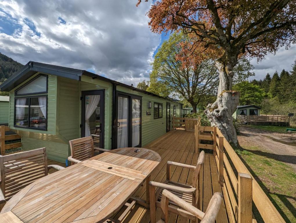 una mesa de madera y sillas en una terraza con una casa en The Castleton 20, en Ardentinny