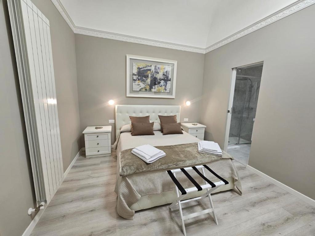 a white bedroom with a bed and a chair at City Rooms Katane in Catania