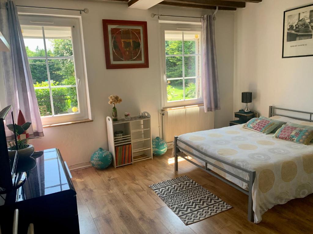 ein Schlafzimmer mit einem Bett und zwei Fenstern in der Unterkunft Le Margouillat 
