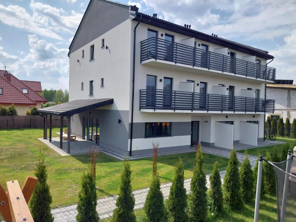 une maison blanche avec des balcons bleus et une cour dans l'établissement VILLA EDEN USTKA wypoczynek dla dorosłych, à Ustka